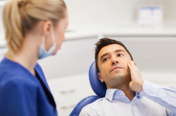 man holding his injured jaw talking to nurse